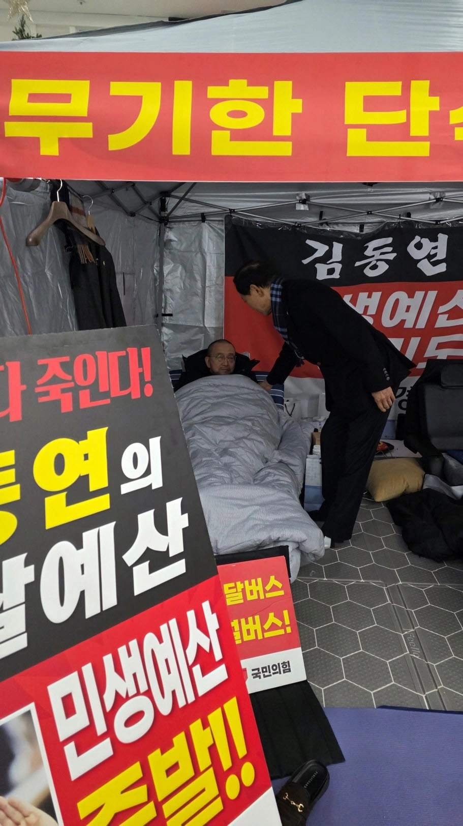 윤재영 의원이 농성장 천막에서 단식 10일째를 맞은 백현종 국민의힘 대표의원을 찾아 건강 상태를 살피며 대화를 나누고 있다(사진=경기도의회)