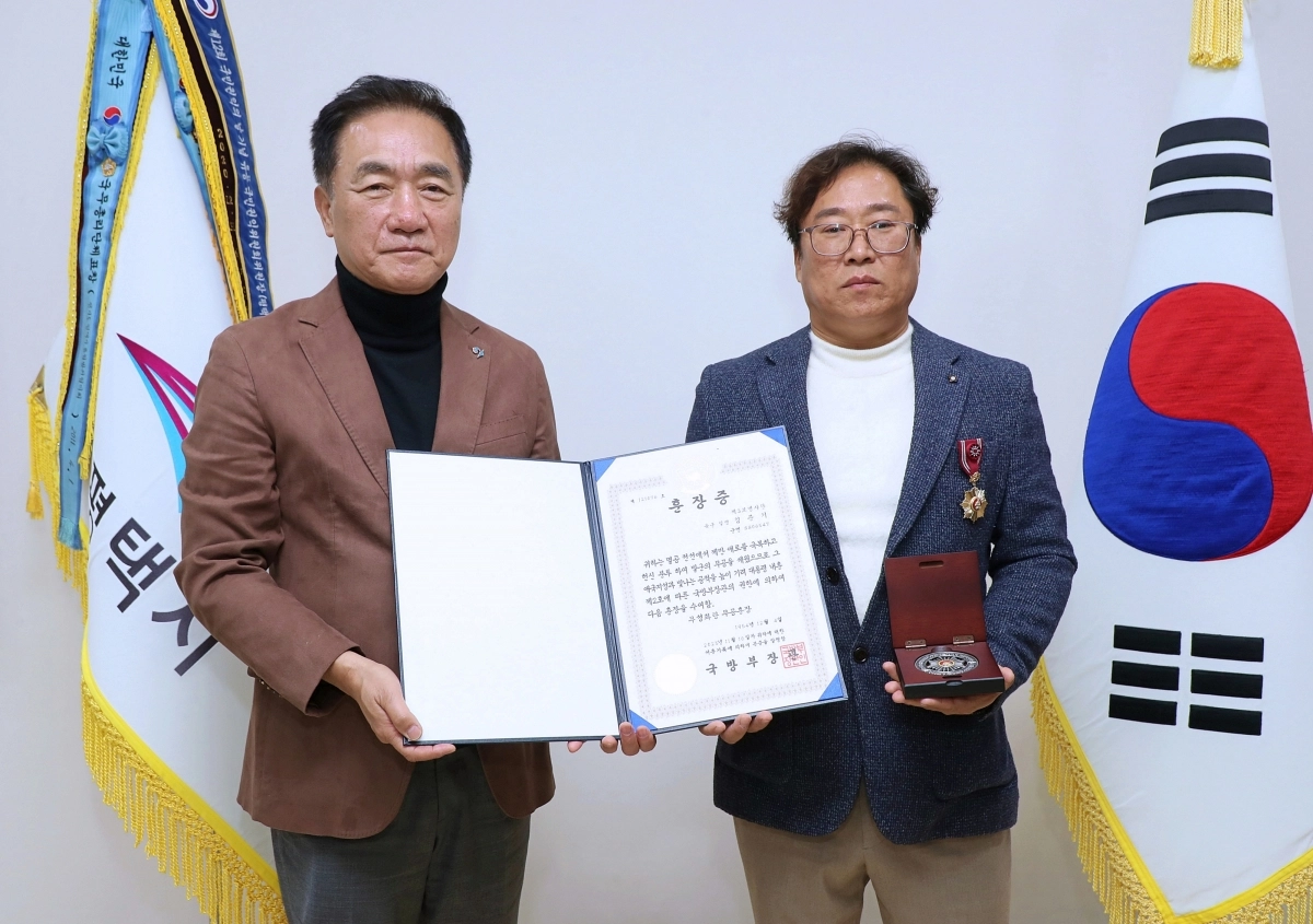 10일 정장선 평택시(오른쪽)이 평택시 모곡동에 거주하는 무공훈장 故 김준기 씨의 손자에게 국방부 장관을 대신해 훈장을 전달했다.  (평택시 제공)