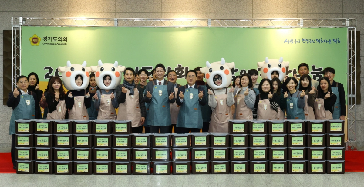 김진경 의장과 의회 관계자들이 11일 의회에서 열린 ‘2025년 사랑의 김장 나눔 행사’에서 도내 취약계층에게 전달할 김치 상자 앞에서 손하트를 그리며 기념촬영을 하고 있다.(사진=경기도의회)