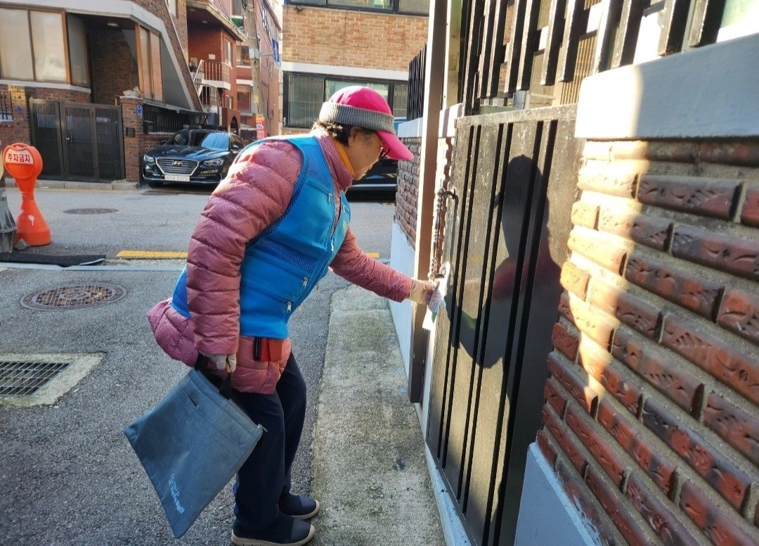 ‘구석구석발굴단’ 단원이 지난달 한 위기가구를 찾아 문고리에 관련 안내문을 부착하는 모습. 성북구 제공