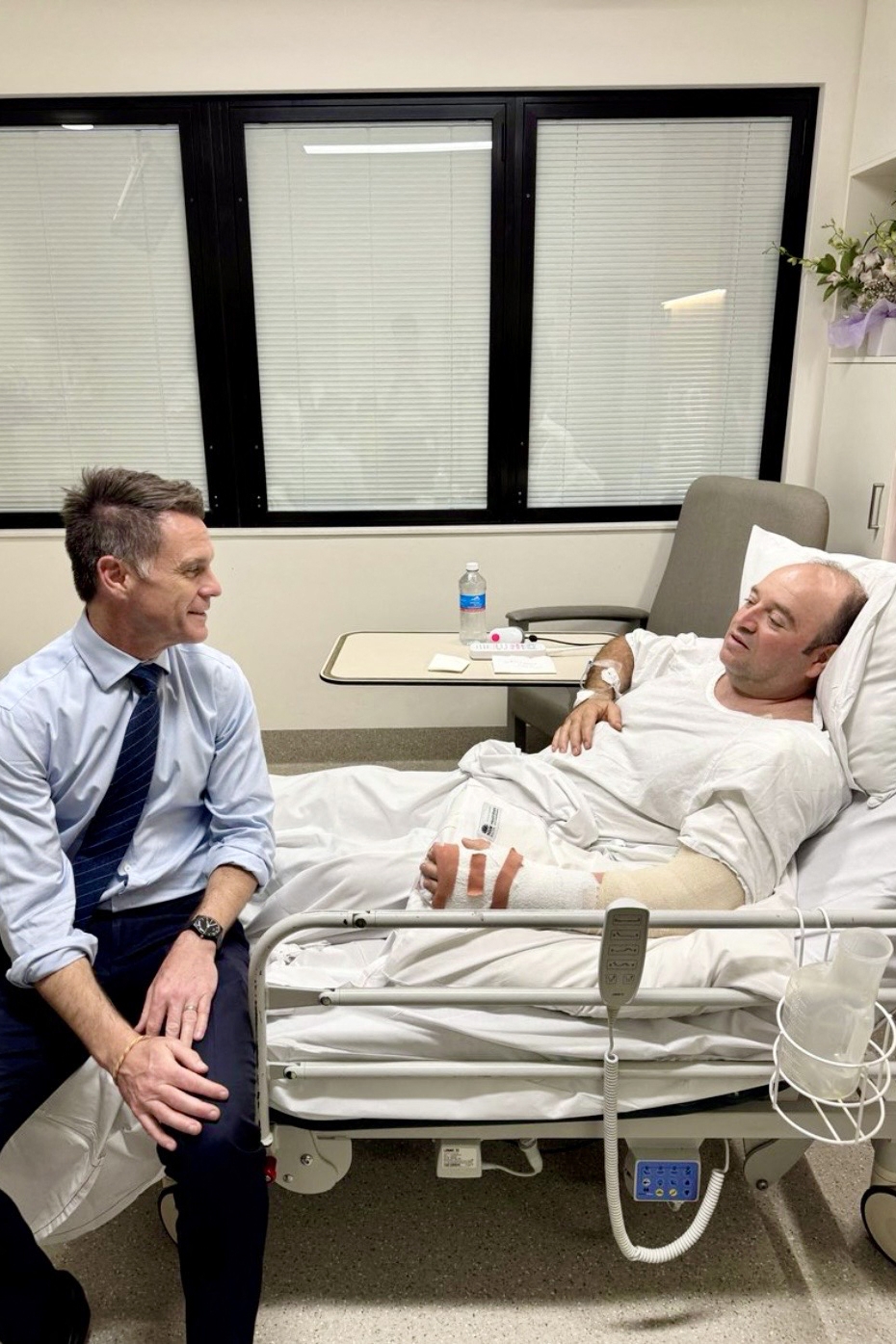 호주 시드니 본다이 해변 유대인 행사장 총격범 가운데 한 명을 제압한 아흐메드 알 아흐메드(오른쪽)가 15일(현지시간) 세인트조지병원에서 크리스 민스 뉴사우스웨일스 주총리와 대화하고 있다. 뉴사우스웨일스 주총리실 제공