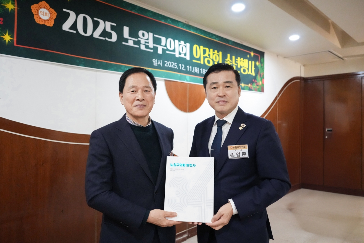 손영준(오른쪽) 노원구의회 의장이 ‘2025 노원구의회 의정회 송년행사’에서 ‘노원구의회 발전사’ 책자를 들고 기념 촬영을 하고 있다. 사진: 노원구의회 제공.