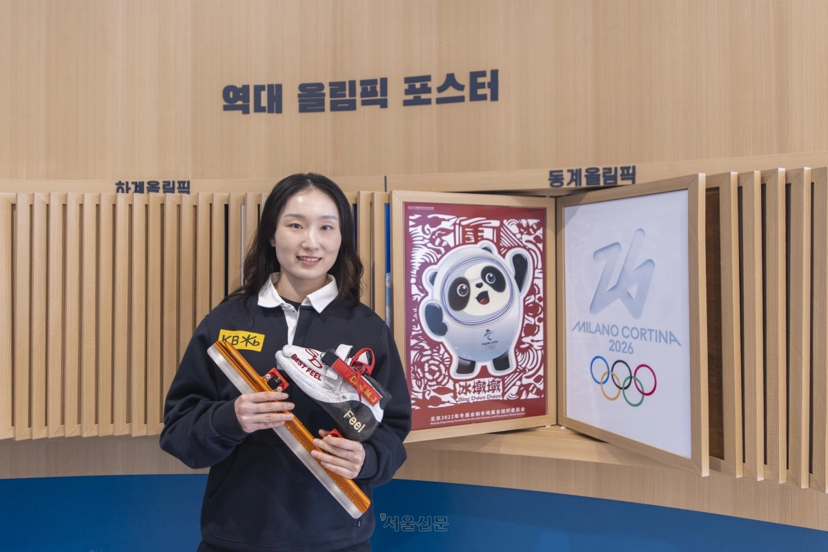 최민정이 17일 충북 진천선수촌에서 경기 때 신는 스케이트를 들고 2022 베이징 동계올림픽 포스터(왼쪽)와 밀라노·코르티나담페초 동계올림픽 포스터 옆에 서서 기념사진을 찍고 있다. 진천 류재민 기자