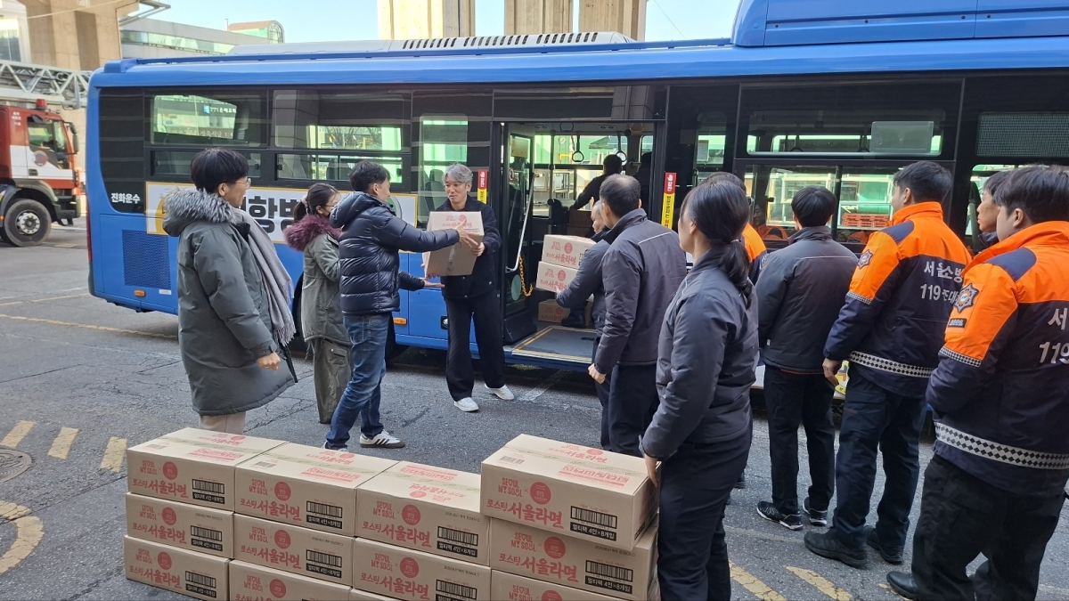 서울시버스운송사업조합 관계자들이 22일 마천동 송파소방서에서 ‘우리시대의 히어로 소방관 응원 행사’를 열고 시내버스로 싣고 온 서울라면을 소방관들에게 전달하고 있다. 서울시버스운송사업조합 제공