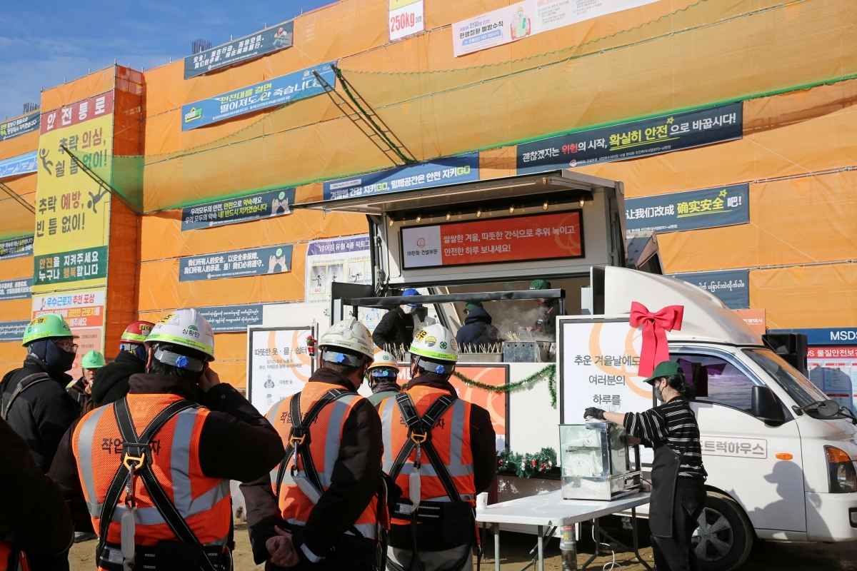 한화  건설부문 건설현장 근로자들이 ‘찾아가는 겨울간식차’를 찾아 호빵과 어묵을 즐기고 있다. 한화 건설부문 제공