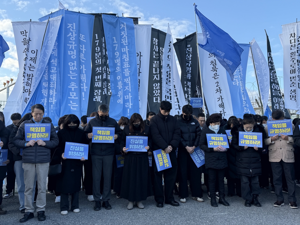 제주항공 여객기 참사 1주기를 하루 앞둔 28일 오후 무안국제공항 외곽도로에서 만장행진을 한 참사 유가족들과 시민들이 희생자들을 위해 묵념을 올리고 있다. 2025.12.28 뉴스1