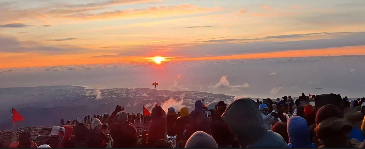 병오년 새해 첫날 한라산 백록담 정상에 오른 탐방객들이 구름 사이로 뜨는 해를 바라보며 휴대전화에 일출의 장관을 담고 있다. 한라산국립공원관리소 제공