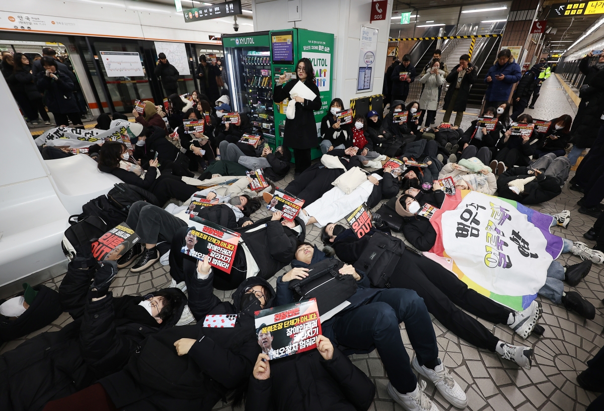 전국장애인차별철폐연대가 지난해 12월 24일 오전 서울 종로구 안국역에서 출근길 승강장 다이인(die-in)행동을 열자 참가자들이 바닥에 눕는 퍼포먼스를 진행하고 있다. 2024.12.24. 연합뉴스