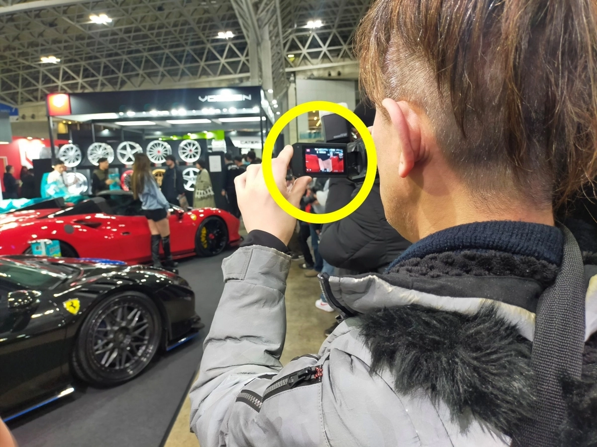 일본 레이싱모델 세나 히나노는 하반신만 확대해 촬영하는 것을 멈춰달라고 호소했다. 사진은 세나의 하반신을 확대해(노란 원) 촬영하는 남성의 뒷모습. 세나 히나노 엑스(X) 캡처