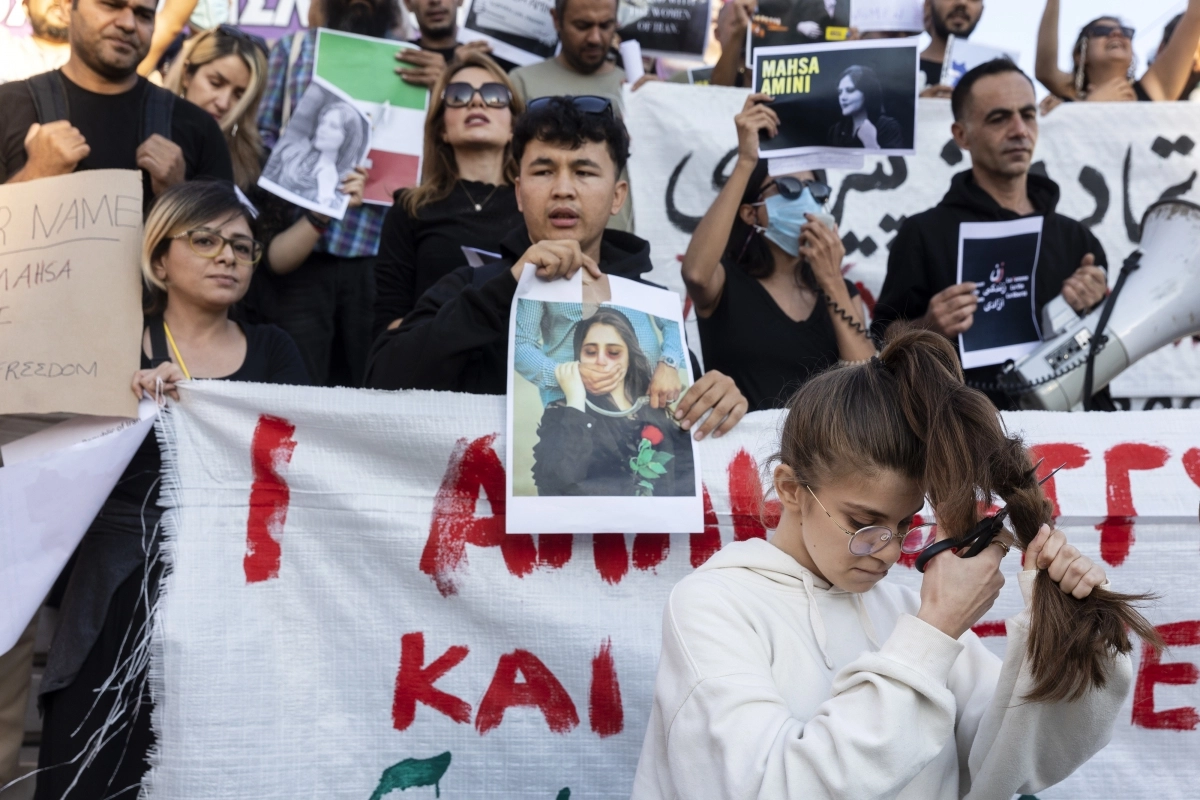 2022년 9월 그리스 아테네에서 히잡을 느슨하게 착용했다는 이유로 체포돼 의문사한 이란 여성 마흐사 아미니를 추모하는 시위에서 한 여성이 가위로 자신의 머리를 자르며 분노를 표하고 있다. 아테네 AP 연합뉴스