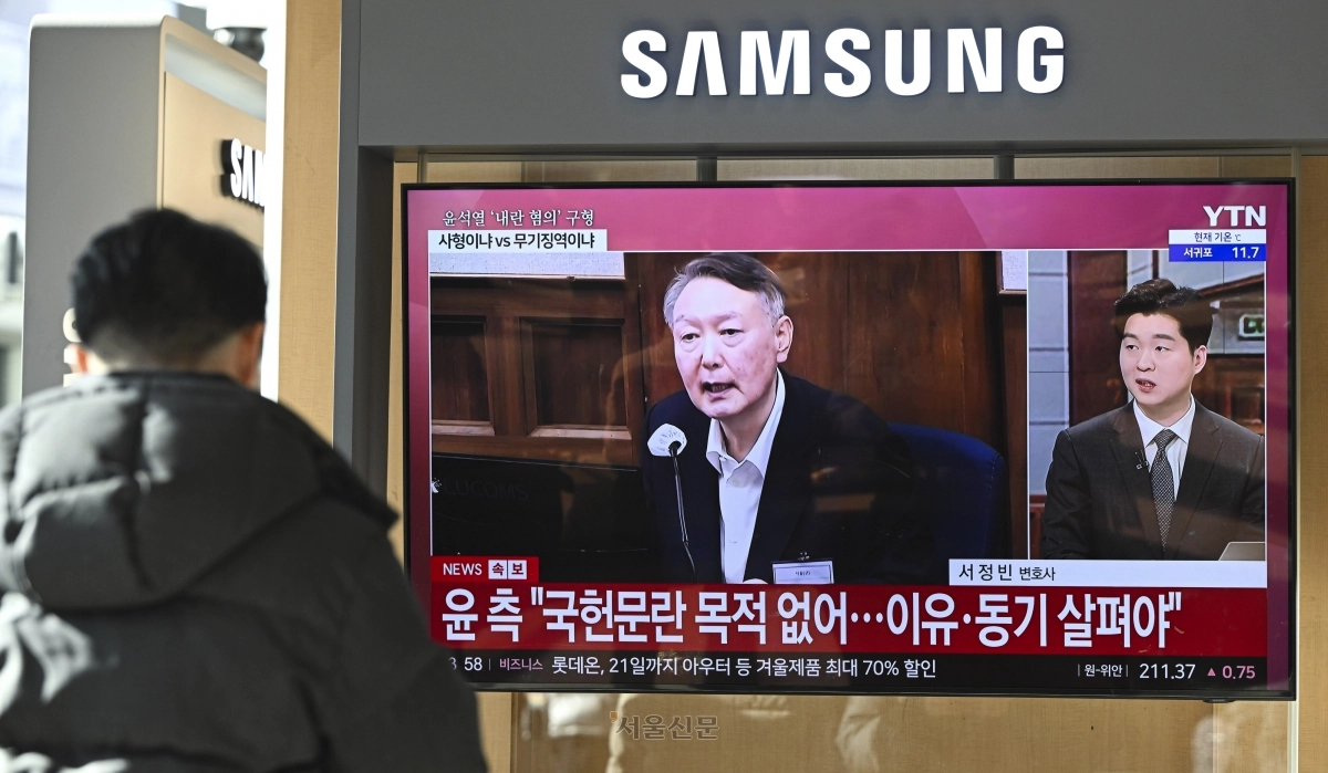 윤석열 전 대통령의 내란 우두머리 혐의 결심공판이 열린 13일 서울역 대합실에서 시민들이 관련 뉴스를 시청하고 있다.   이지훈 기자