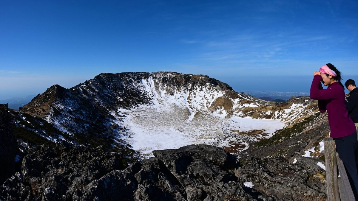 백록담 북벽 난간에 서서 사진을 찍고 있는 등산객.