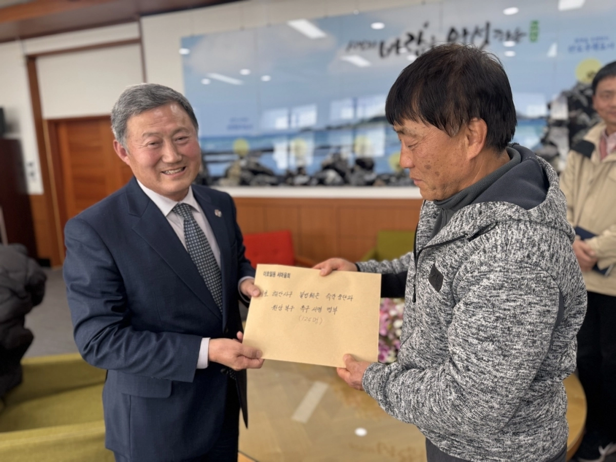 김상철 이호1동 서마읋회장이 김완근(왼쪽) 제주시장에게 이호 해안사구 원상복구를 결의한 주민 서명지를 전달하고 있다. 이호일동 해안사구 지킴이 비상대책위원회 제공