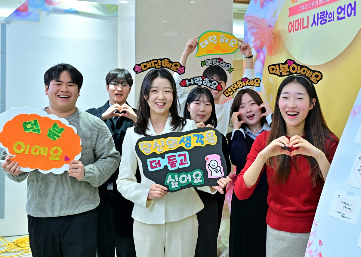 경기도 성남시 새예루살렘 판교성전 포토존을 찾은 ‘어머니 사랑의 언어’ 세미나 참석자들이 머리띠, 손팻말 등을 들고 활짝 웃고 있다. 하나님의 교회 제공.