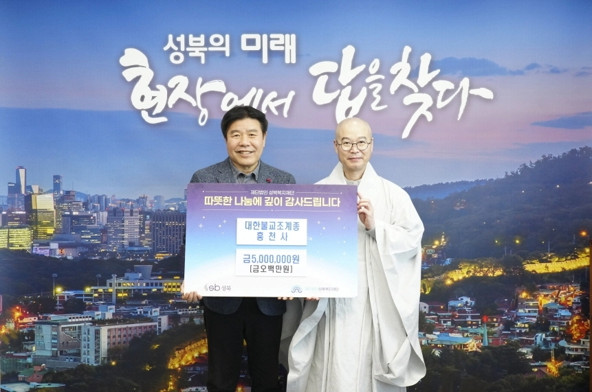 윤재성(왼쪽) 성북복지재단 이사장이 지난 20일 성북구청에서 대한불교조계종 흥천사 주지 각밀 스님에게 기부금을 전달받으면서 기념촬영을 하고 있다. 성북구 제공