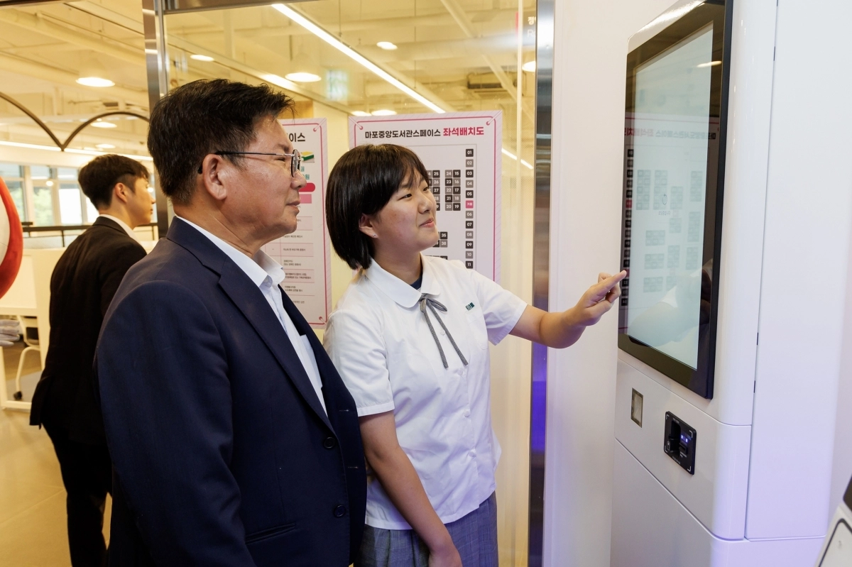 박강수(왼쪽) 마포구청장이 공공 스터디카페 ‘마포나루스페이스’에서 한 학생에게 키오스크 사용법을 배우고 있다. 마포구 제공