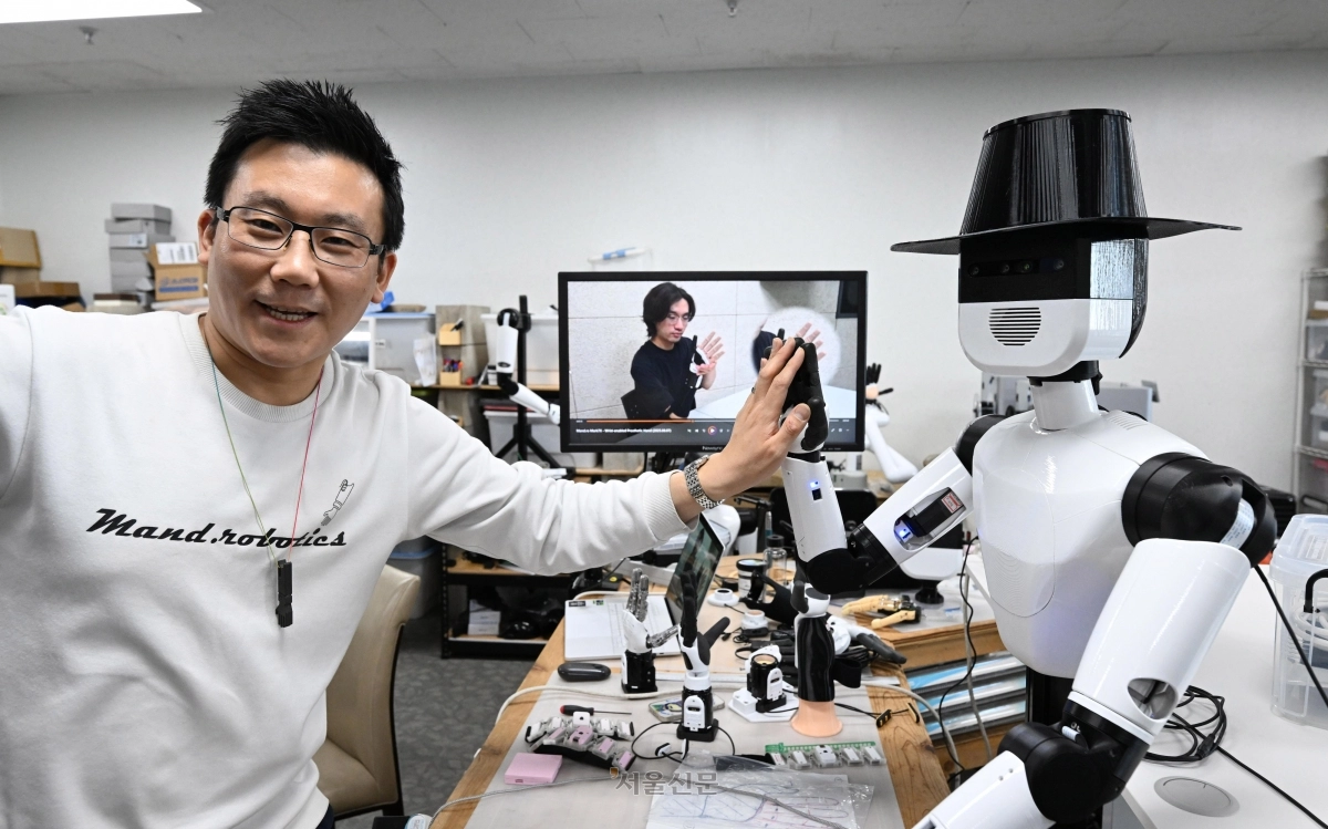 이상호 만드로 대표가 지난달 22일 경기 부천시 만드로 사무실에서 휴머노이드 로봇에 부착한 로봇 의수 ‘마크7’와 손을 맞대는 ‘하이 파이브’ 동작을 시연하고 있다. 도준석 전문기자