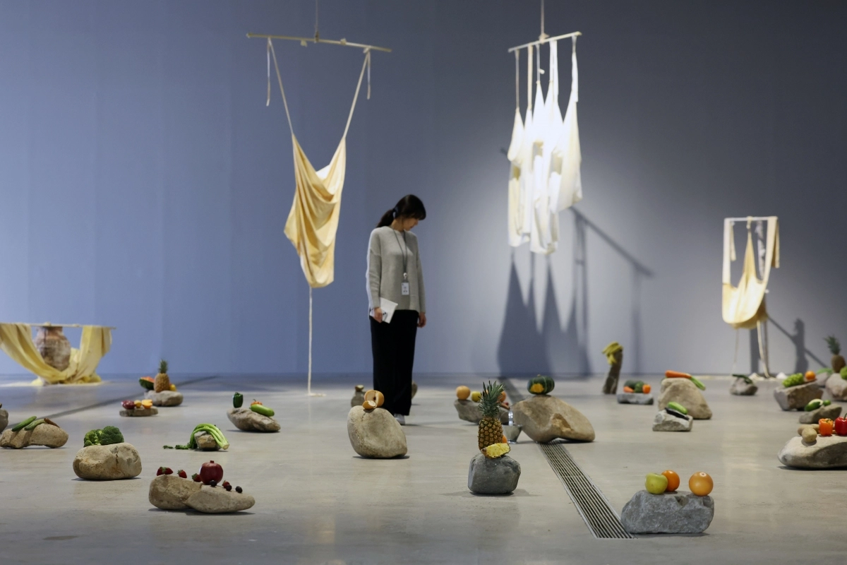 과테말라 중부 칵치켈 부족의 전통에서 비롯된 에드가 칼렐의 작품 ‘고대 지식 형태의 메아리’ 모습. 돌을 제단 삼아 과일과 야채가 올려져 있다. 천장에는 박테리아, 곰팡이, 곤충과 같은 존재와 협업하는 것으로 유명한 댄 리 작가의 ‘목격자’가 걸려 있다. 강황으로 염색한 직물 조각은 이전 작품에 활용됐던 천을 재활용한 것이다. 뉴시스