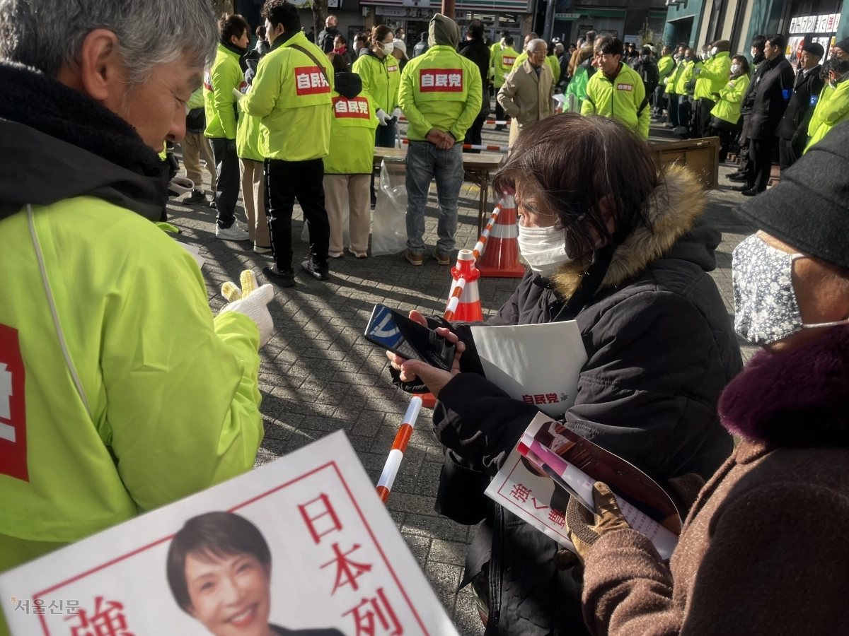 자민당 스태프가 배포한 다카이치 총리의 주요 정책이 담긴 팸플릿을 살펴보는 일본 유권자들. 명희진 특파원
