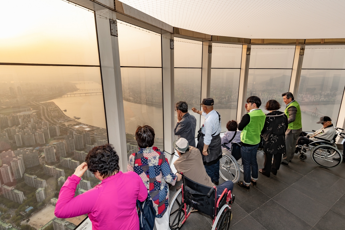 서울 잠실 롯데월드타워의 스카이 전망대를 찾은 장애인과 가족들. 롯데월드는 관광 약자를 위한 온라인 우대 제도를 도입해 다양한 관광 편의를 제공할 예정이다. 롯데월드  제공.