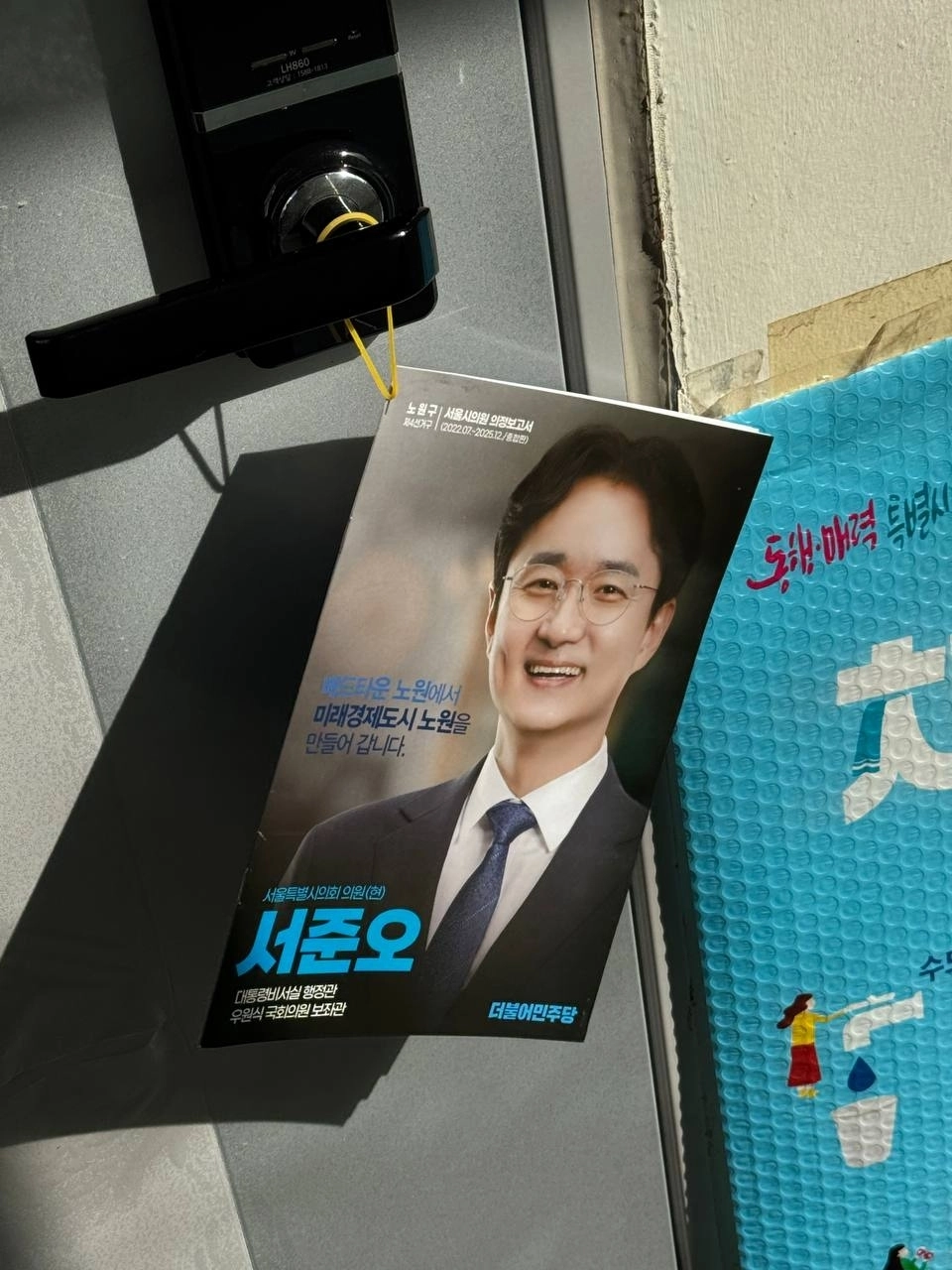 현관문 손잡이에 고무줄로 걸어놓은 의정보고서