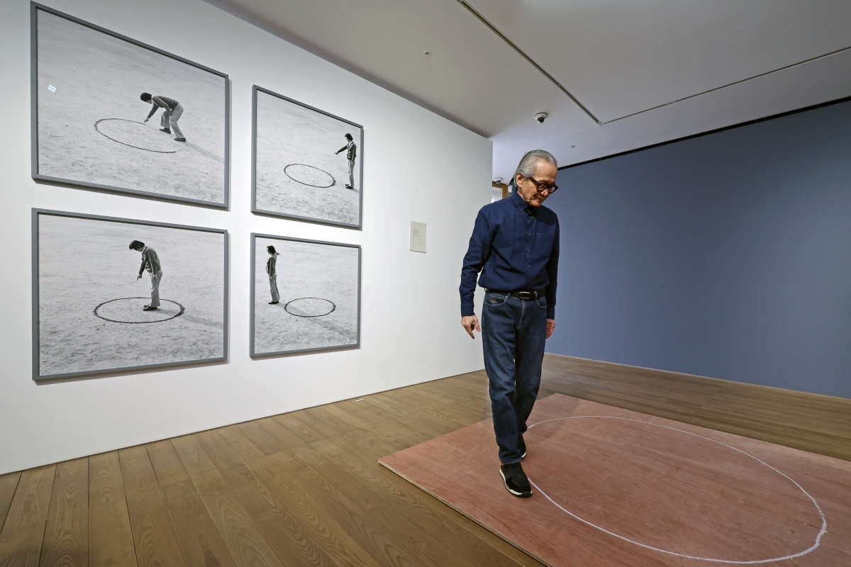 이건용 작가가 지난 4일 서울 용산구 페이스 갤러리에서 1975년 홍익대 운동장에서 선보였던 퍼포먼스 ‘장소의 논리’를 재연하고 있다. 작가 뒤로 1975년 퍼포먼스 당시 사진이 걸려 있다. 뉴시스