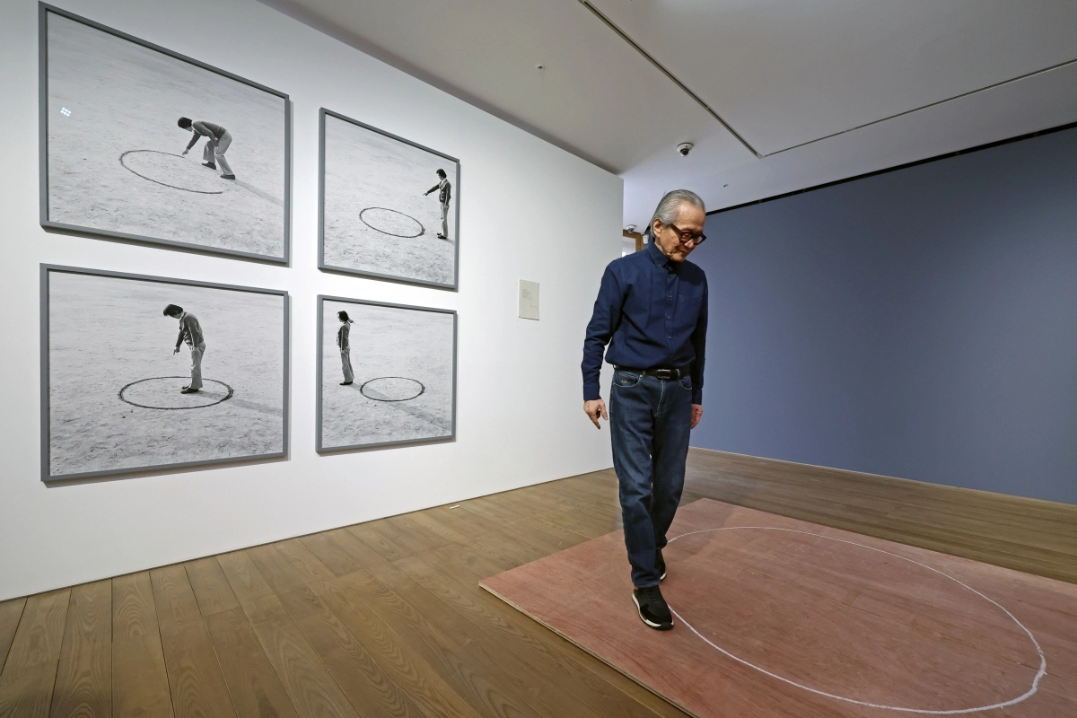 이건용 작가가 지난 4일 서울 용산구 페이스 갤러리에서 1975년 홍익대 운동장에서 선보였던 퍼포먼스 ‘장소의 논리’를 재연하고 있다. 작가 뒤로 1975년 퍼포먼스 당시 사진이 걸려 있다. 뉴시스