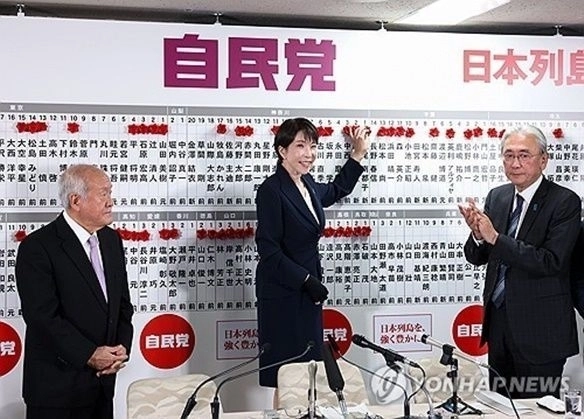 일본 총리이자 자민당 총재인 다카이치 사나에가 8일 도쿄 자민당 본부에서 총선에 당선된 자민당 후보 이름 위에 장미를 달며 미소를 보이고 있다.  도쿄 AP 연합뉴스