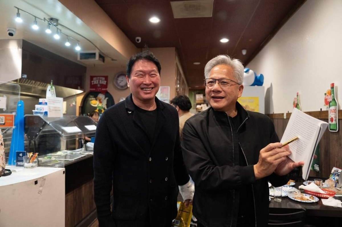 지난 5일(현지시간) 미국 캘리포니아 산타클라라의 한국식 호프집 ‘99치킨’에서 가진 최태원 SK그룹 회장과의 만찬회동에서 젠슨 황 엔비디아 최고경영자가 신간 ‘슈퍼모멘텀’을 펼쳐보이고 있다. 사진=연합뉴스