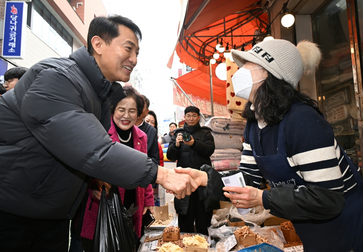 오세훈(왼쪽 첫 번째) 서울시장이 13일 광진구 자양전통시장을 방문해 온누리상품권으로 견과류를 구매한 후 상인과 명절 인사를 나누고 있다. 서울시 제공