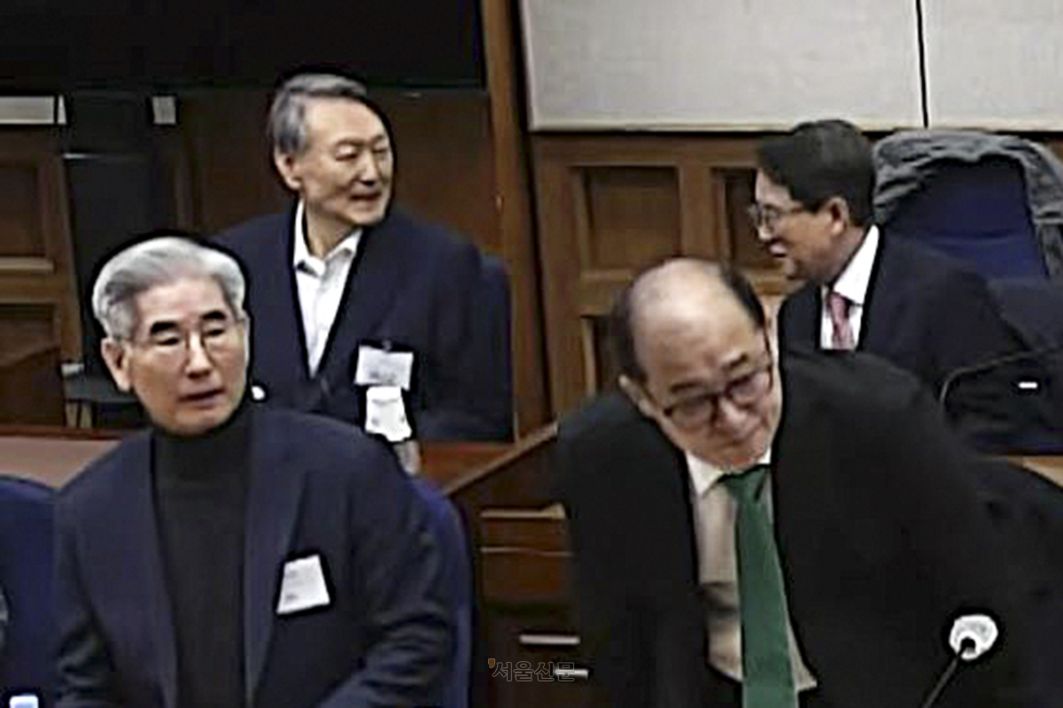 윤석열 전 대통령이 19일 오후 서울 서초구 서울중앙지방법원에서 열린 12·3 비상계엄 관련 내란 우두머리 혐의 사건 1심 선고공판에 출석해 변호사와 대화하며 웃고 있다. 유튜브 캡처