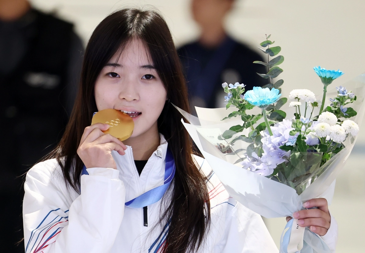 한국 소노보드 국가대표 최가온이 16일 인천국제공항을 통해 귀국하며 2026 밀라노·코르티나 동계올림픽 여자 하프파이프에서 따낸 금메달을 깨물고 있다. 연합뉴스