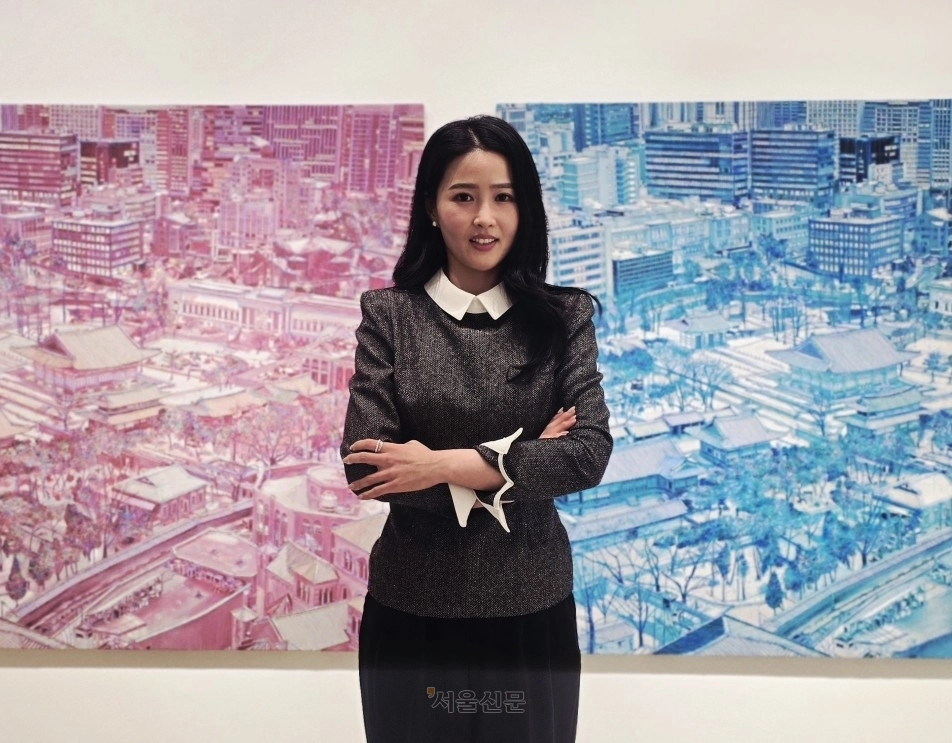 김란 작가가 덕수궁 일대의 모습을 두 가지 톤으로 표현한 두 작품 사이에서 기념촬영을 하고 있다.