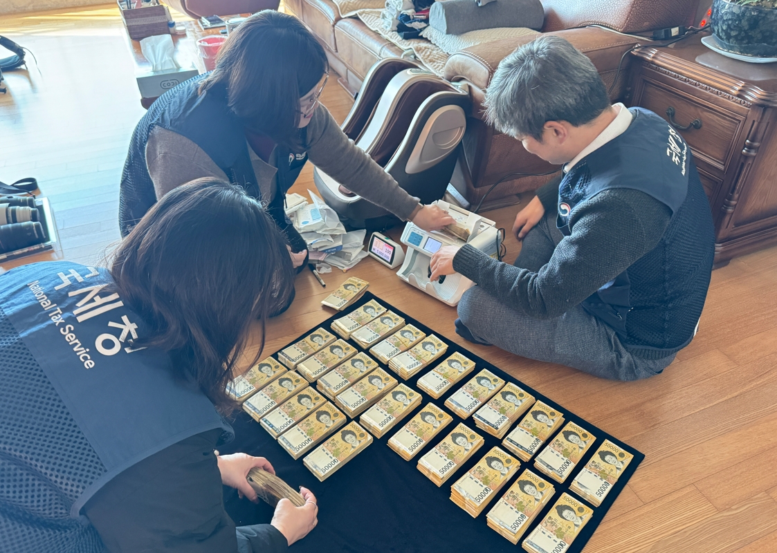 부산의 한 고액체납자 자택 수색에 나선 국세청 특별기동반 요원들이 김치통 속에 숨겨진 현금 뭉치를 발견하고 압류를 위해 액수를 확인하고 있다. 국세청 제공