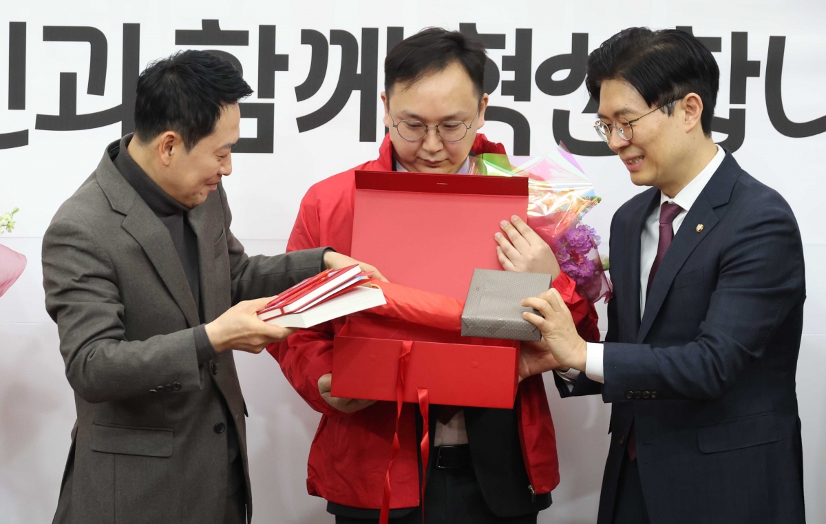 장동혁 국민의힘 대표와 조정훈 인재영입위원장이 25일 국회에서 열린 인재영입위원회 영입인재 환영식에서 정진우(가운데) 원전엔지니어에게 국민의힘 시크릿박스를 전달하고 있다. 뉴시스