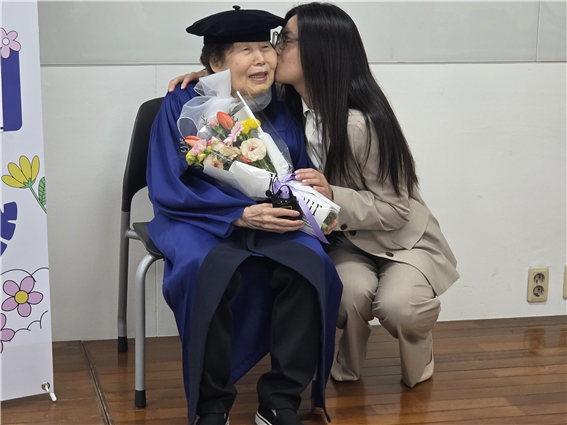 김정자(왼쪽) 할머니의 졸업을 축하하기 위해 미국 보스턴에서 온 32세 손녀가 27일 숙명여대 사회교육관 강의실에서 진행된 인터뷰 도중 김 할머니에게 꽃다발을 건네며 입을 맞추고 있다. 김신우 수습기자