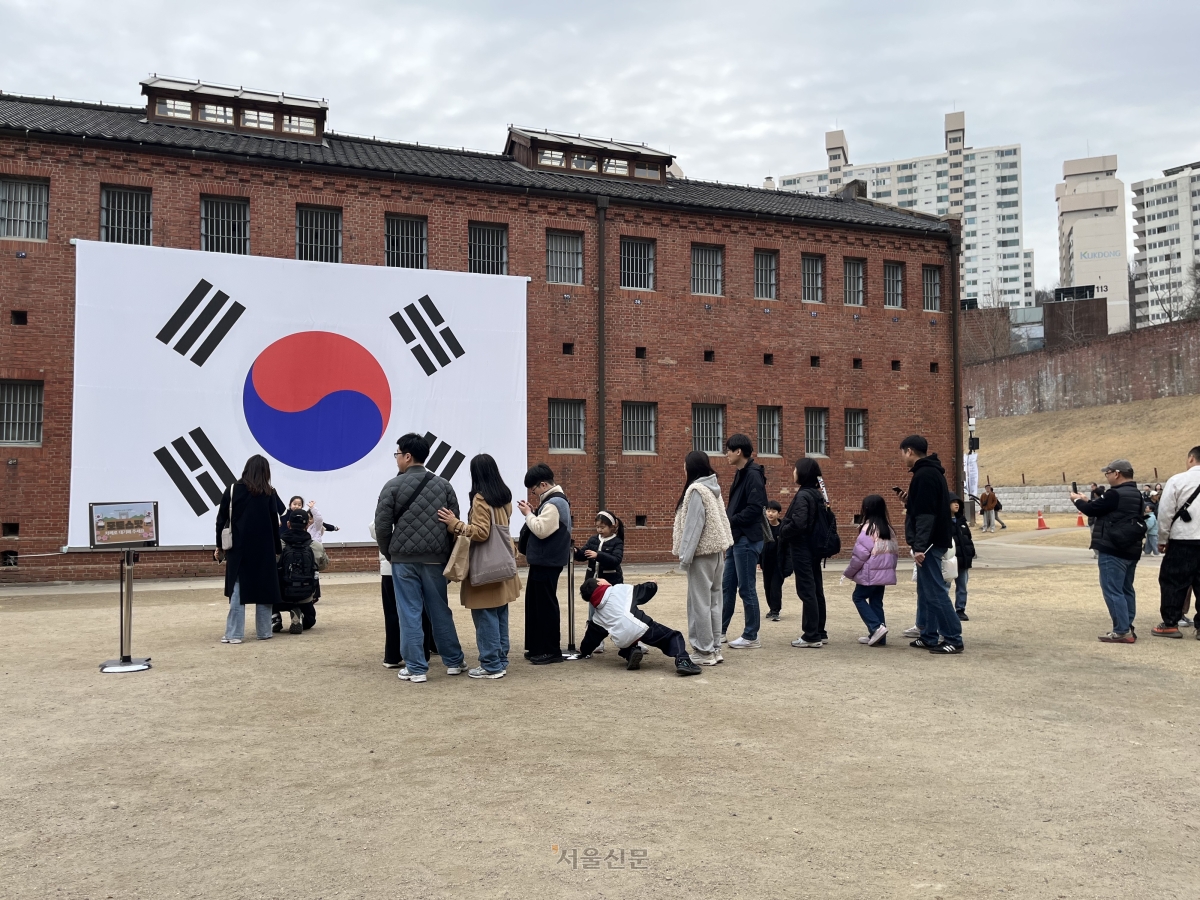 3·1절인 1일 서울 서대문구 서대문형무소를 찾은 시민들이 대형 태극기 앞에서 기념촬영을 하기 위해 줄을 서 있다.