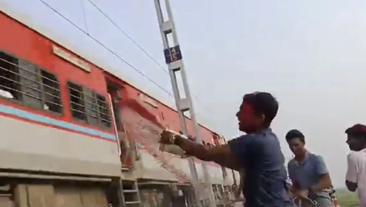 선로 옆에 서 있는 남성들이 고속으로 지나치는 열차를 향해 소똥과 흙탕물을 양동이째 퍼붓는 모습. 엑스(X) 캡처