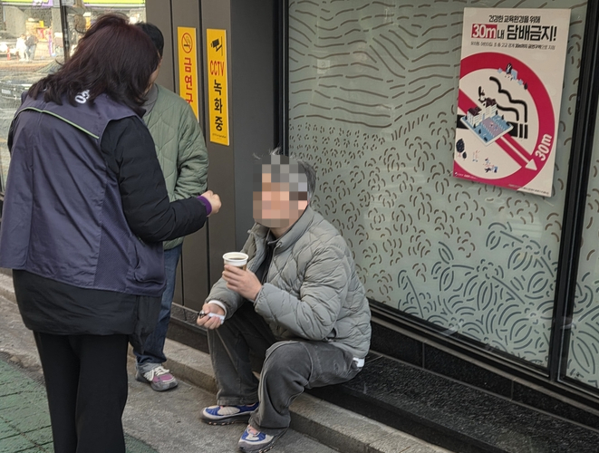 서울 중구 보건소 흡연단속원이 남산초 인근에서 전자담배를 피우는 40대 남성A씨를 제지하고 있다. A씨 뒤로 학교 인근 흡연을 금지하는 포스터가 붙어 있다. 김신우 수습기자