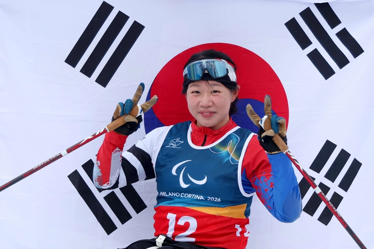 김윤지가 15일(한국시간) 이탈리아 테세로 크로스컨트리 스타디움에서 열린 2026 밀라노·코르티나담페초 동계패럴림픽 크로스컨트리 스키 여자 20㎞ 인터벌 스타트 좌식에서 우승한 뒤 태극기 앞에서 기념사진을 찍고 있다. 대한장애인체육회 제공