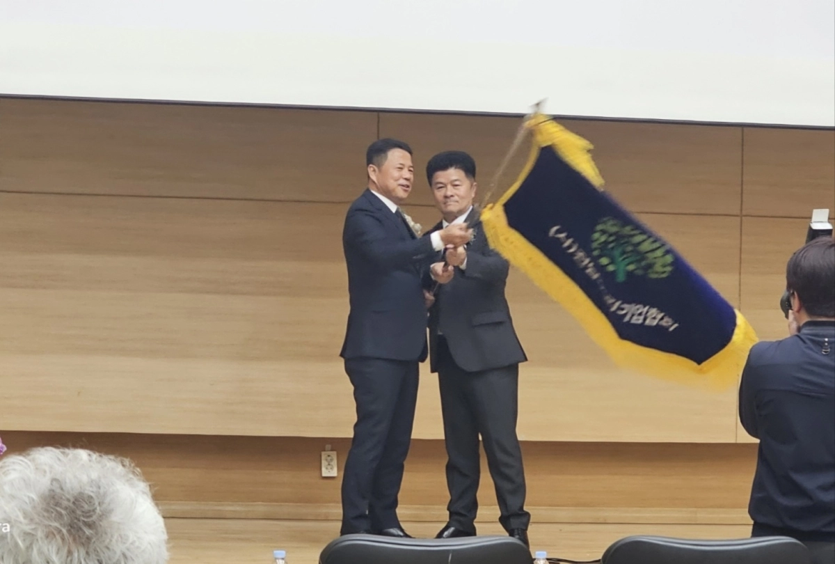 기순도 신임 회장과 이호재 이임회장이 협회 기를 흔들고 있다.