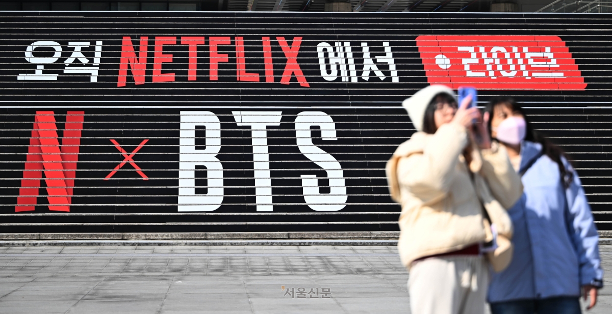 외국인 관광객들이 12일 서울 광화문 세종문화회관 계단에서 그룹 방탄소년단(BTS)의 컴백을 알리는 홍보물을 배경으로 기념촬영을 하고 있다. 방탄소년단은 오는 3월 21일 광화문 광장 일대에서 3년 9개월 만에 ‘완전체’로 돌아와 기념 공연을 개최한다. 2026.3.12 홍윤기 기자