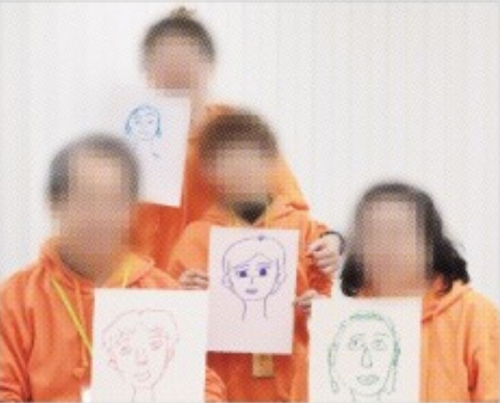 수도권의 한 교도소에서 18일 열린 ‘가족사랑캠프’ 행사에서 수용자와 가족이 직접 그린 그림을 든 채 기념촬영을 하고 있다. 법무부 제공