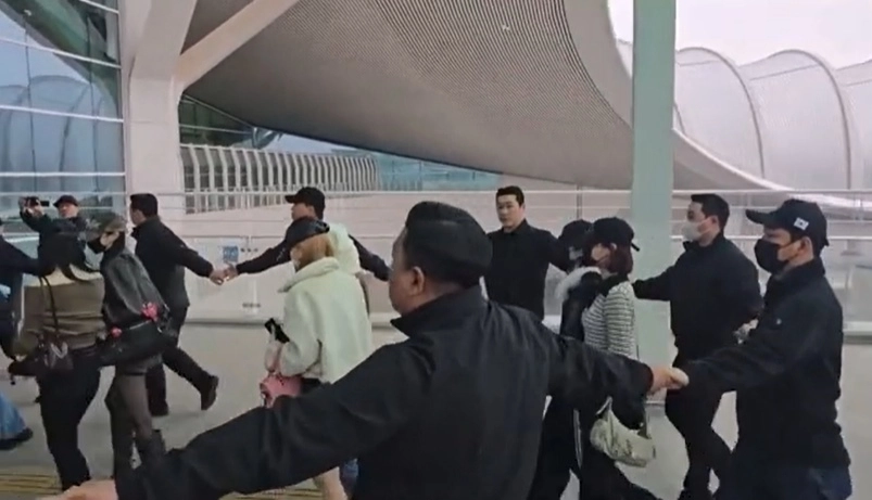 18일 인천국제공항에서 SM엔터테인먼트 소속 걸그룹 ‘하츠투하츠’가 공항 게이트에 들어가려 하자 경비업체 직원들이 ‘인간띠’를 만들어 멤버들을 에워쌌다. 자료 : 온라인 커뮤니티