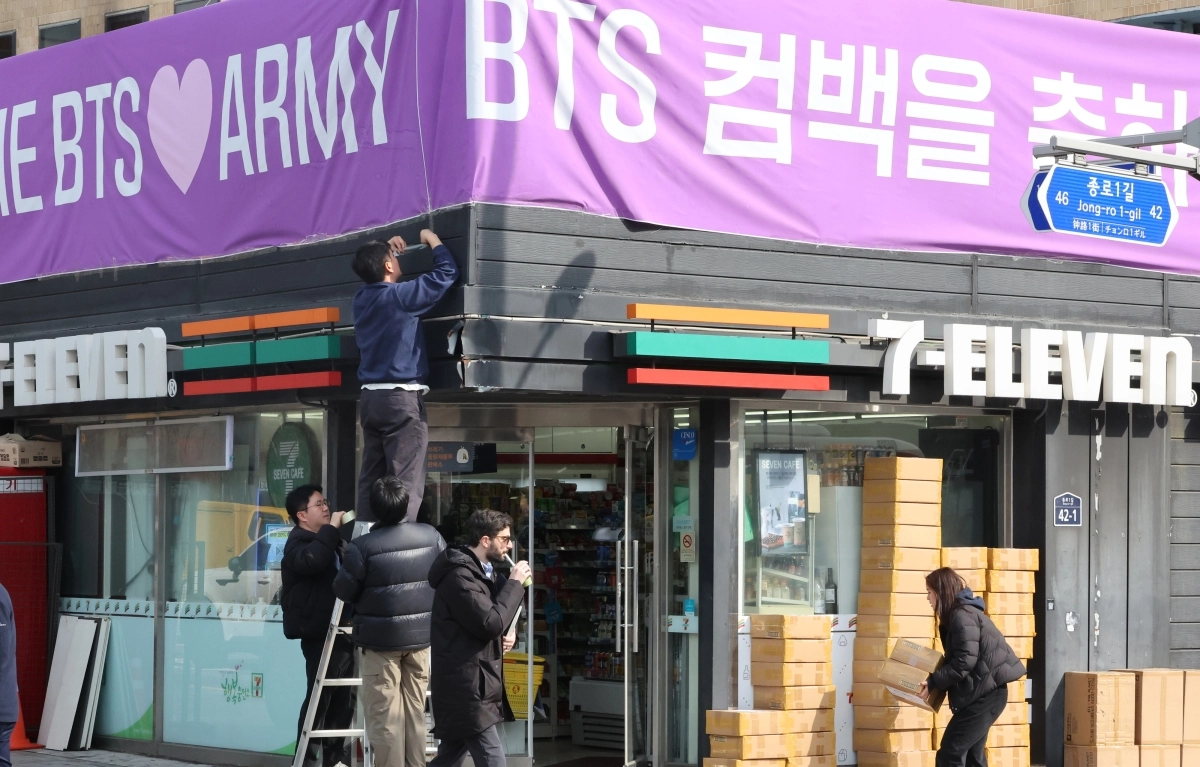 방탄소년단(BTS) 컴백 공연을 앞둔 지난 18일 서울 광화문광장 인근의 한 편의점에서 관계자들이 BTS 팬을 겨냥해 현수막을 설치하고 있다. 연합뉴스