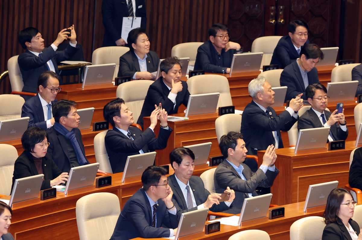 더불어민주당 의원들이 20일 국회 본회의장에서 공소청법안(대안)이 통과되자 휴대폰을 꺼내 사진을 찍고 있다. 연합뉴스