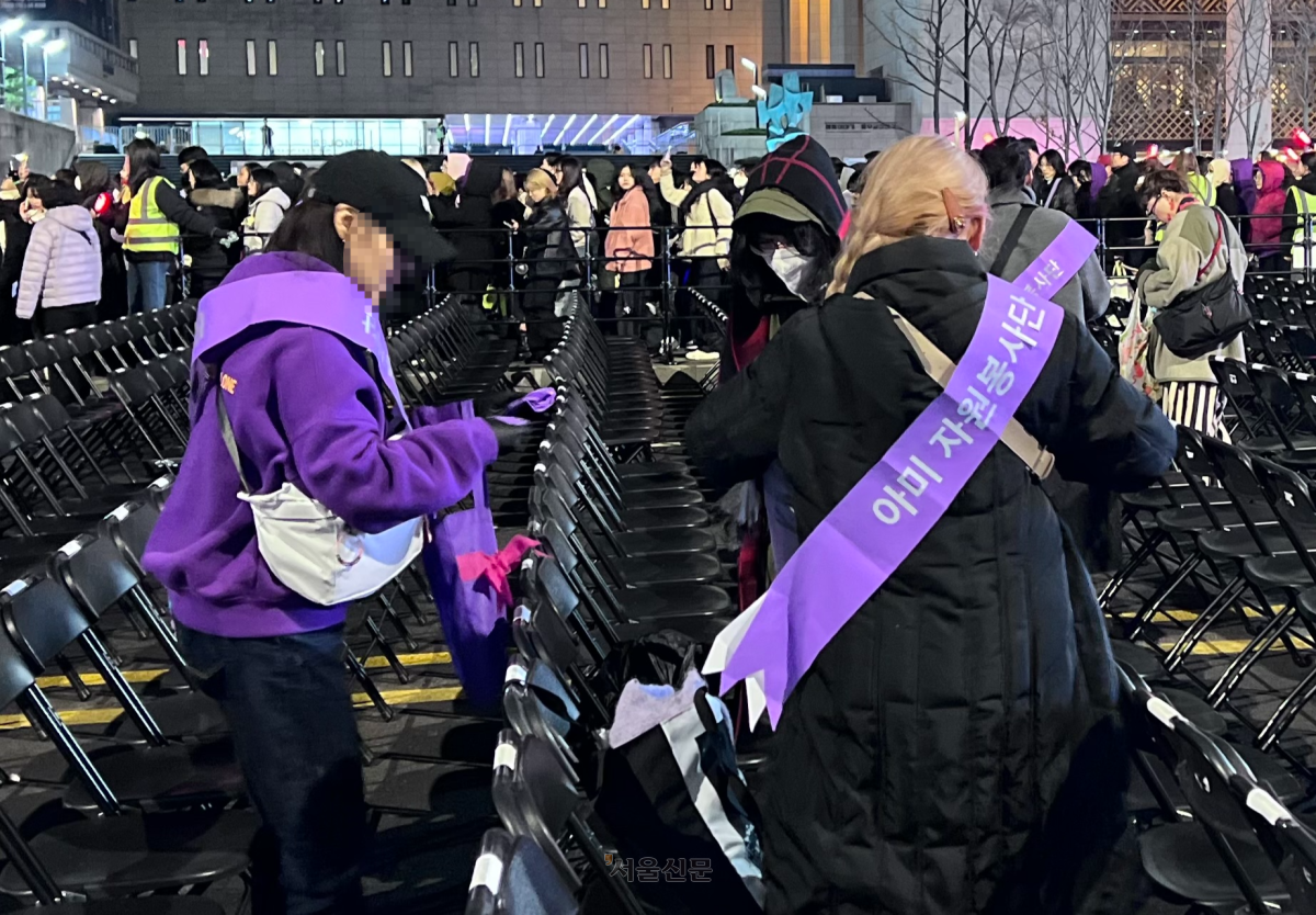 보라색 어깨띠를 두른 ‘아미 자원봉사단’이 21일 그룹 방탄소년단(BTS)의 컴백 공연 직후 서울 종로구 광화문광장 일대를 청소하고 있다. 이지 수습기자