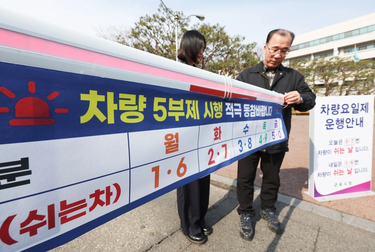 24일 경기도 군포시청에서 관계자들이 25일 0시부터 시작되는 공공부문 승용차 5부제를 앞두고 주차 차단봉에 안내문을 붙이고 있다. 연합뉴스