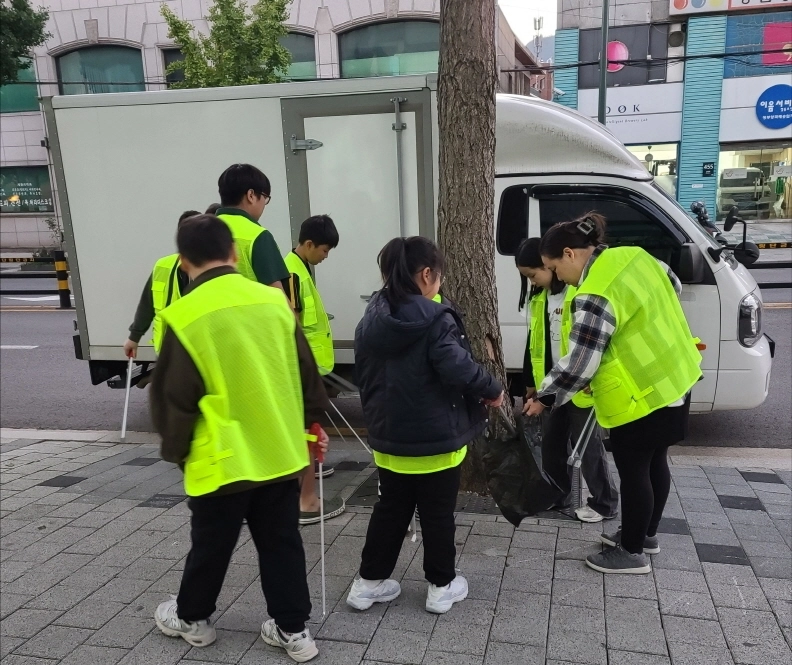 지난해 10월 서울 강북구의 수유동의 한 대로변에서 나무돌보미 활동에 참여하는 시민들이 낙엽을 치우고 있다.  강북구 제공