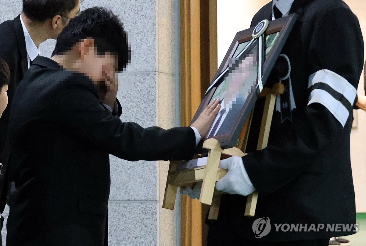 25일 대전 대덕구 안전공업 화재 참사 희생자의 첫 발인식이 엄수된 가운데 아버지를 잃은 초등학생 아들이 고인의 얼굴을 쓰다듬으며 눈물을 흘리고 있다. 대전 연합뉴스